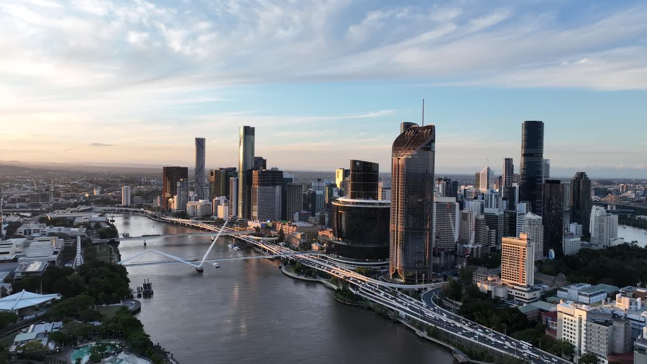 Langsom drone-kredsning ved den gyldne time over Brisbane River, der cirkler Queens Wharf og The Star Brisbane-tårnene med Neville Bonner Bridge og en CityCat-færge i syne, Brisbane, QLD, Australien