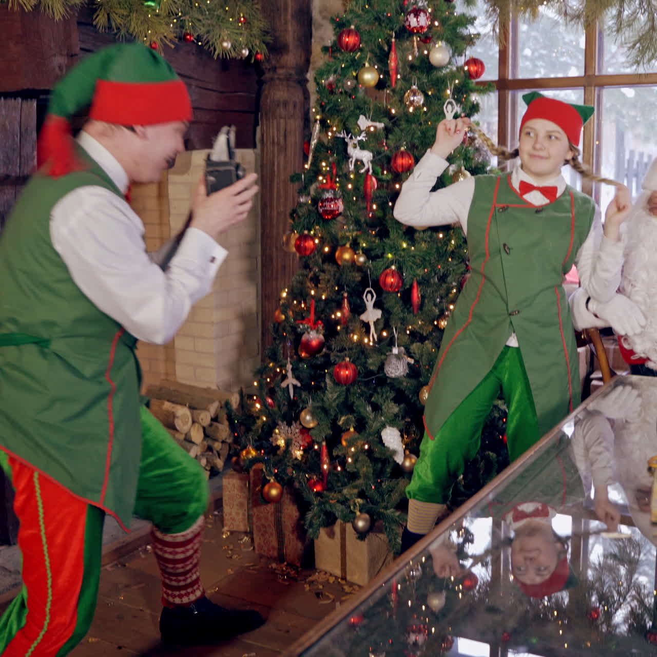 Santa with funny elves at Christmas. Elf is taking photo of Santa and girl elf on Christmas room background. New Year time.