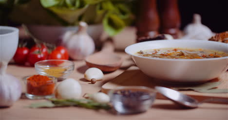 sopa en un tazón en medio de varios ingredientes surtidos en una mesa de madera 9