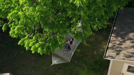 a young girl relaxes in a hammock on a pretty summer day