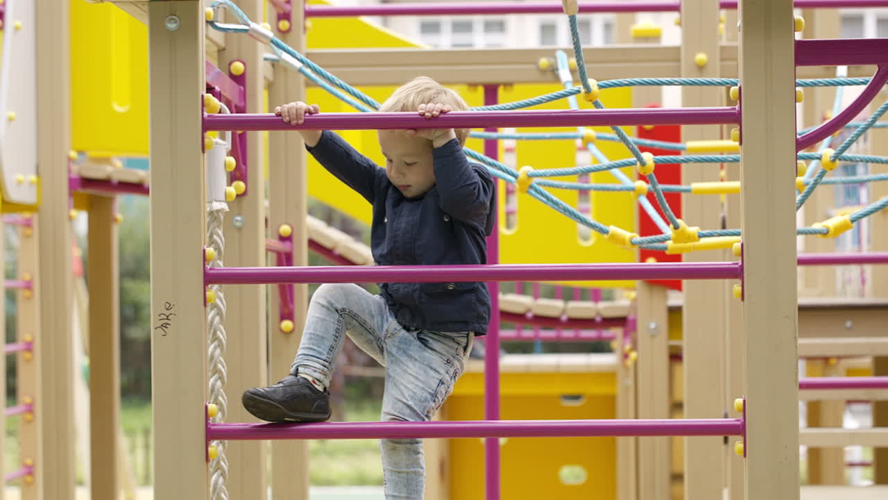 un niño lindo escalando en un gimnasio de la jungla
