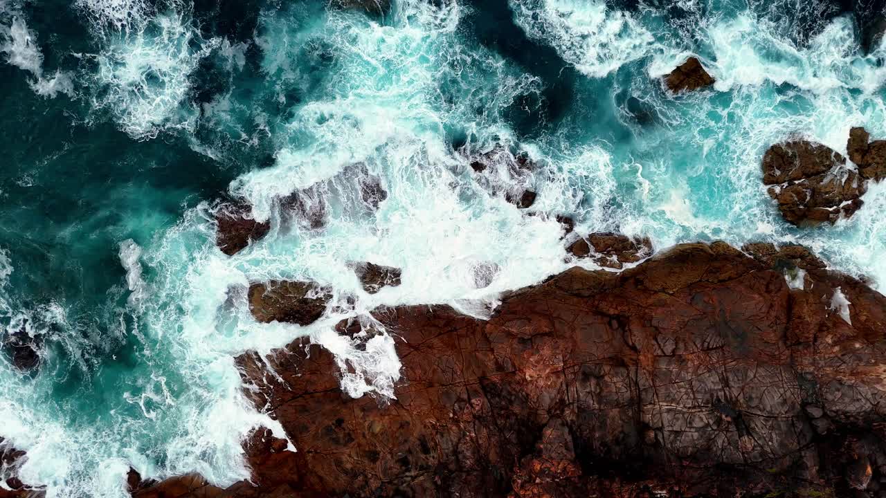 una vista a volo d'uccello di una costa rocciosa con le onde che si infrangono sulle rocce e sull'oceano