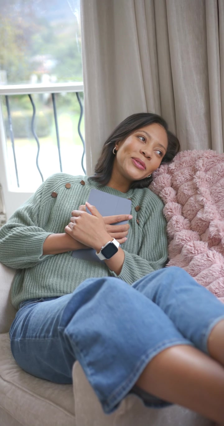 Video verticale: Donna afroamericana che tiene un tablet, parla e poi si rilassa per riposare sul divano.