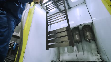 a worker paints a stainless steel metal structure with an airbrush spray gun. dry painting method.