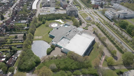 aerial overview of indoor swimming pool with solar panels on roof and solar panel field