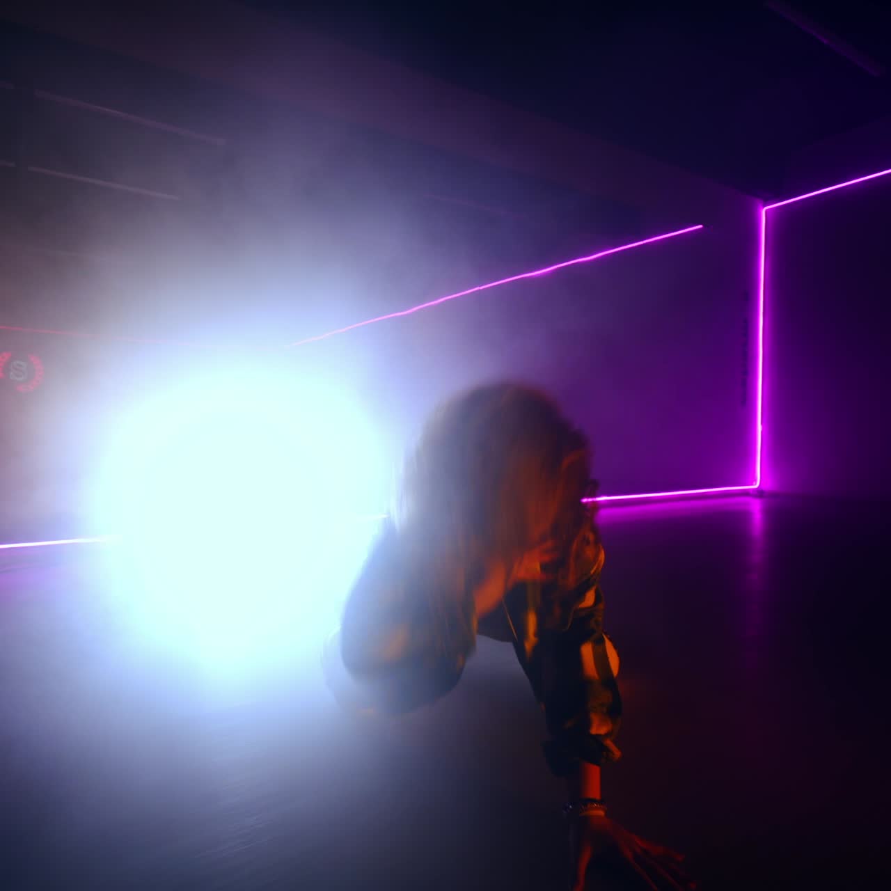 Hip hop female dancer moving in the dark spacious room. Energetic dance style