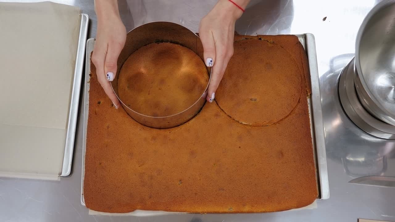 un primer plano de un chef de pastelería cortando una forma redonda de una masa de galleta para un pastel.