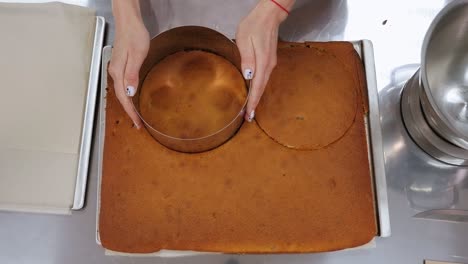 close-up of a pastry chef cuts a round shape from a biscuit dough for a cake.