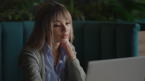 portrait of a beautiful young and attractive asian woman is sitting and looks worried and serious as she broods in front of her laptop computer during the day.