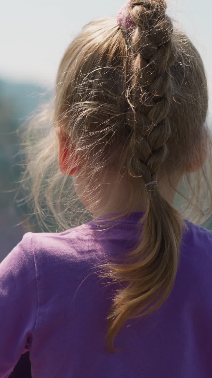짜여진 금발 머리카락을 가진 호기심 많은 어린 소녀는 산악 휴양지에서 로프웨이의 오두막을 타고 하이랜드 뷰를 즐긴다.