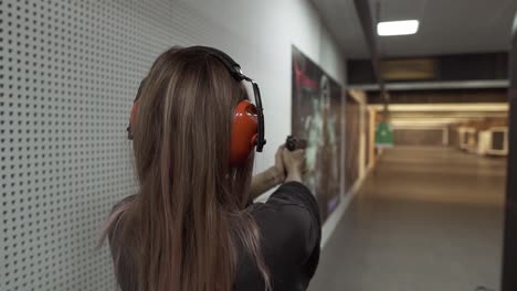 mulher de cabelos longos com fones de ouvido protetores treinando no campo de tiro