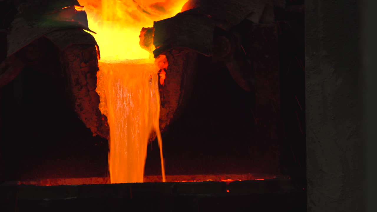 Metallo fuso arancione brillante versato in una fonderia industriale