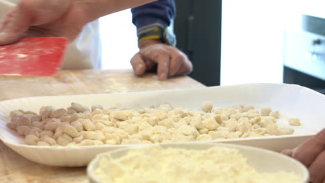 men around a table preparing a typicol type of italian pasta prepared with flour eggs and water