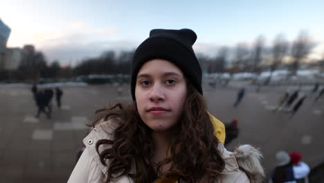 close up portrait of young woman teenager looking into the camera in an urban city in front of a reflective background