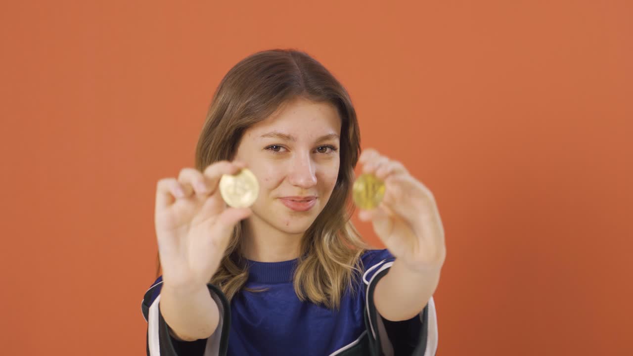 mujer joven sosteniendo bitcoin y mostrándolo.