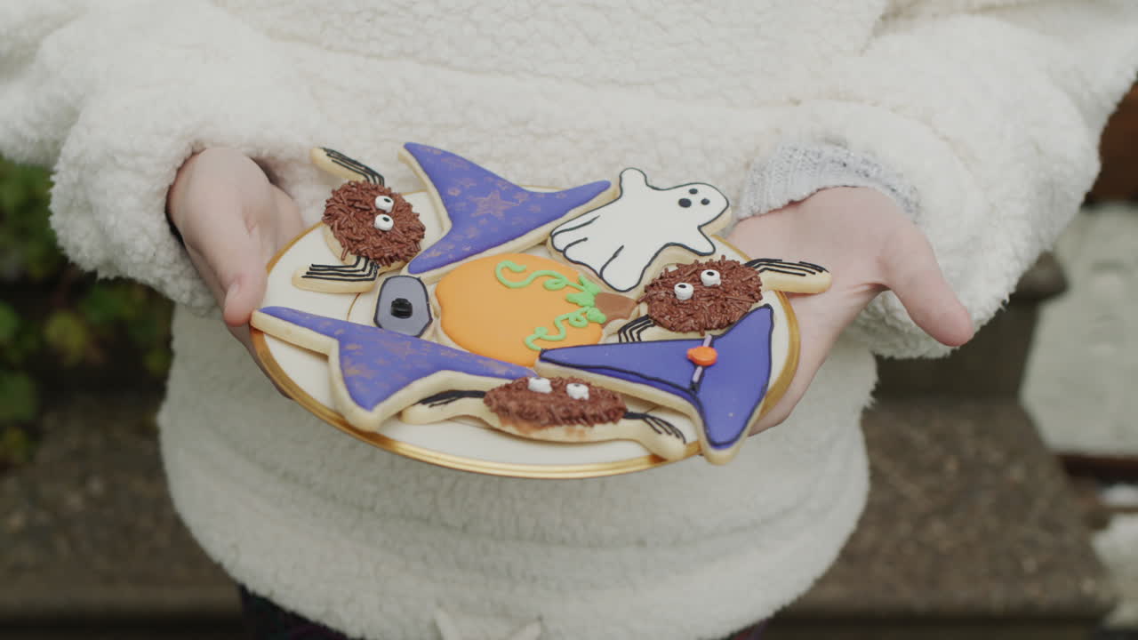 Child holding a plate of handmade Halloween cookies