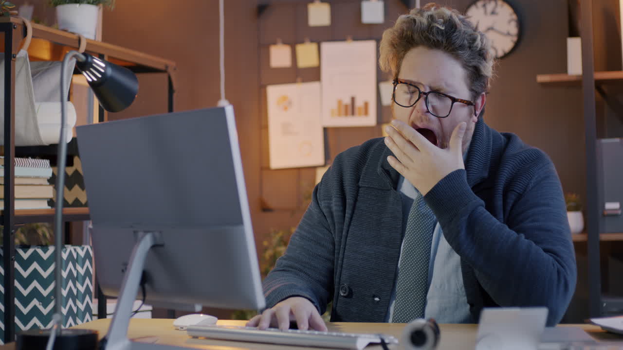 Tired Man Yawning at his Computer in the Office