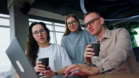 resilient young millennials working in the office. people look at the laptop and discus data drinking coffee.