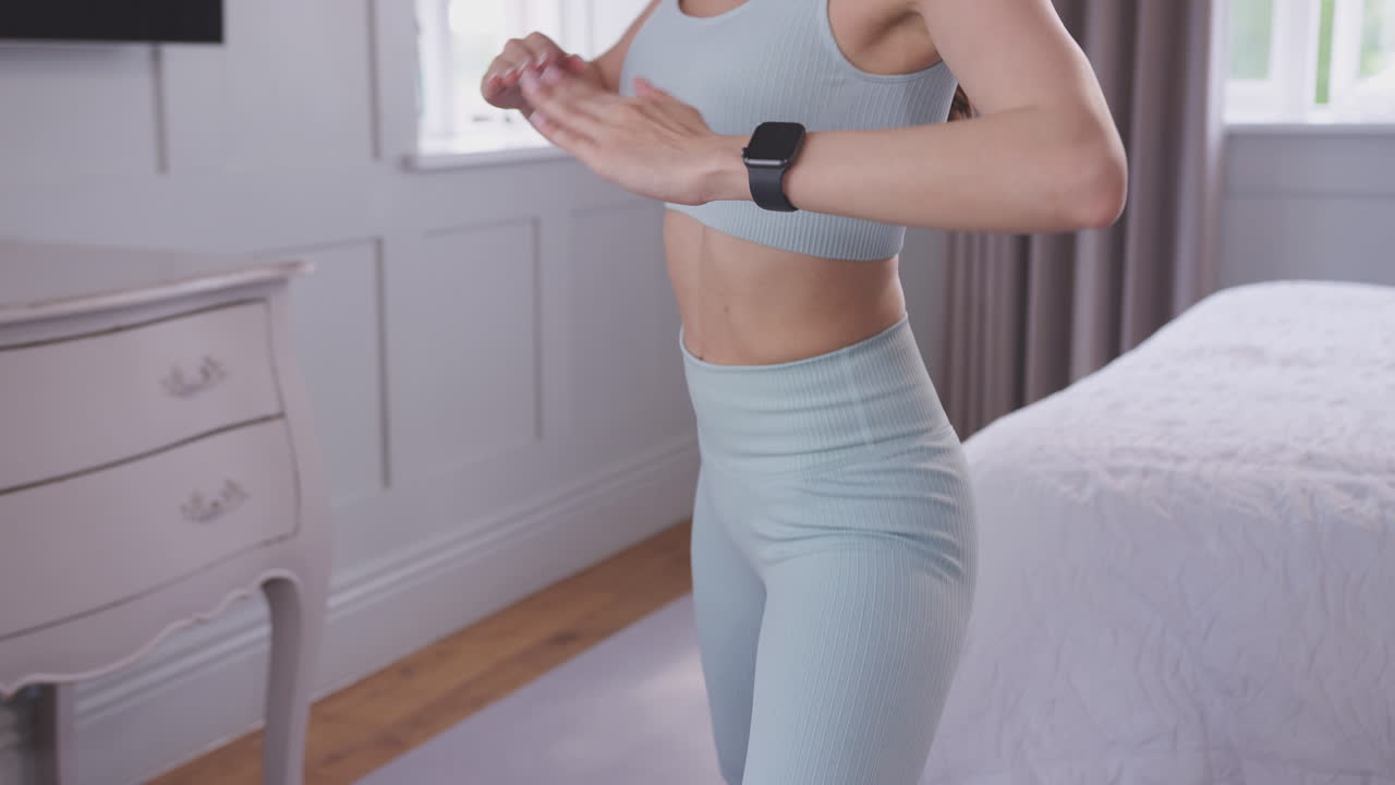 Woman doing yoga standing and stretching on exercise mat in bedroom at home - shot in slow motion