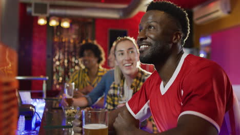video de un grupo diverso de amigos felices bebiendo y viendo juegos deportivos en un bar