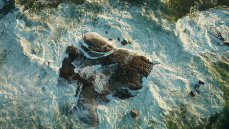 top view of white foaming waves on rocks at oudekraal beach in cape town, south africa - drone, slow motion