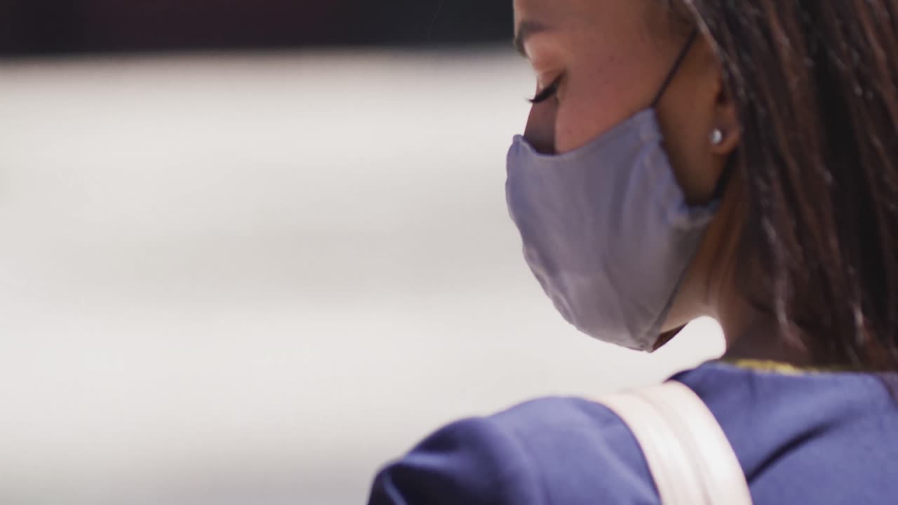 mujer afroamericana con máscara facial caminando por la calle