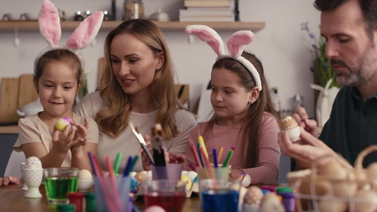 Close up static video of caucasian family of four people decorating easter eggs at home.