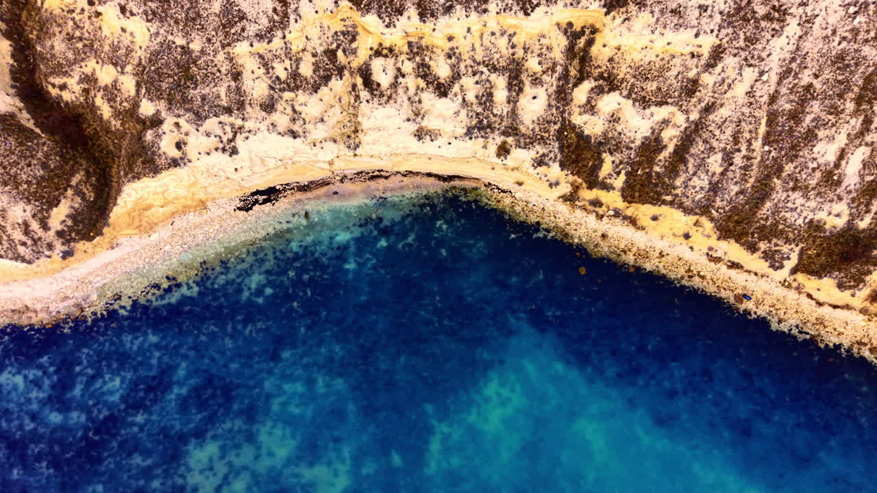 Vista aerea con drone di una costa rocciosa a picco che incontra il mare blu scuro. Vista dall'alto con drone della costa a picco.