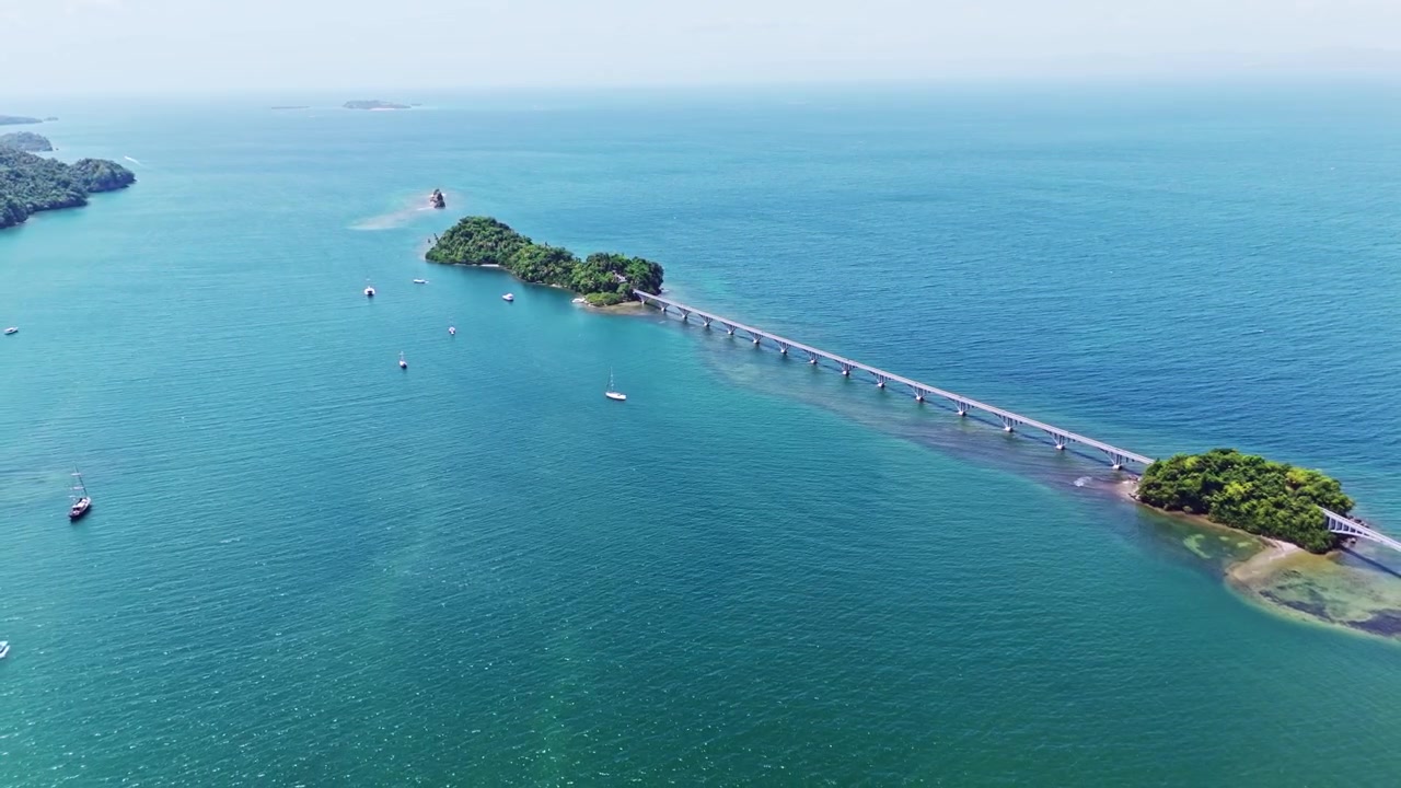 Vista aerea di un ponte pedonale che collega la costa a Cayo Linares e Cayo Vigia nella Baia di Samaná, Repubblica Dominicana. Ripresa in allontanamento ascendente.