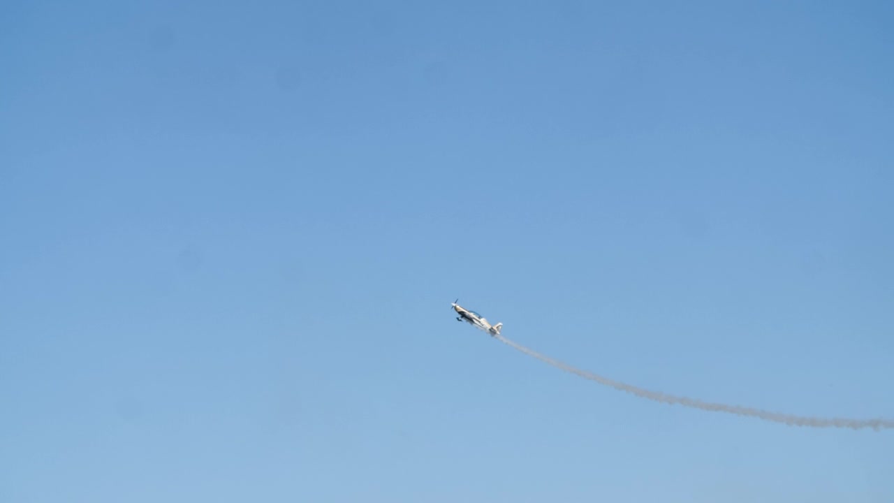 Un aereo si lancia in una discesa mozzafiato allo spettacolo aereo di Oeiras, dettagliata ripresa in slow motion con tracciamento mentre si innalza contro il cielo blu aperto