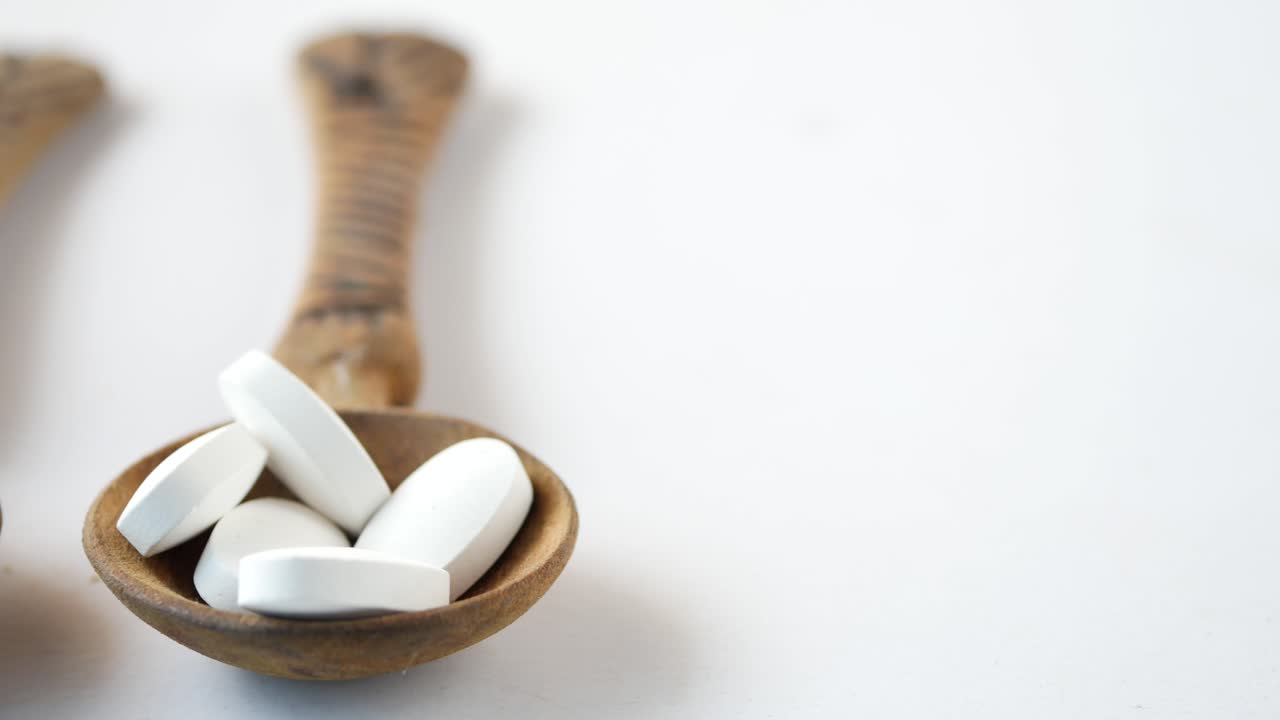 cucharas de madera con pastillas y cápsulas