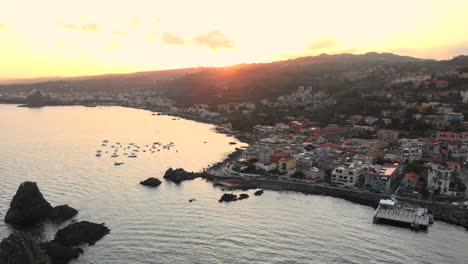 aéreo, ciudad costera italiana de acitrezza, puesta de sol de fondo, arco de derecha a izquierda