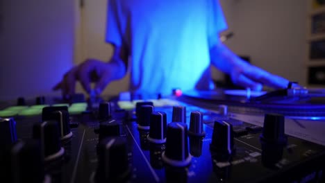 DJ-Mixing-And-Scratching-Vinyls-On-A-Turn-Table-While-Colored-Lights-Flash-Ultra-Wide-Lens-Foreground-Focus