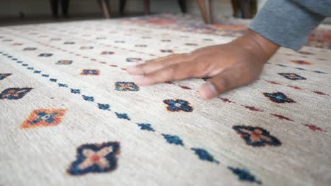 person's hand touching a patterned rug