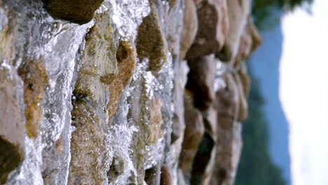 Vertical-of-a-clear-stream-running-through-stone-boulders-Abundant-river-flowing-in-slow-motion