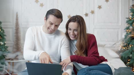 relaxing couple looking christmas presents on pc in modern apartment.