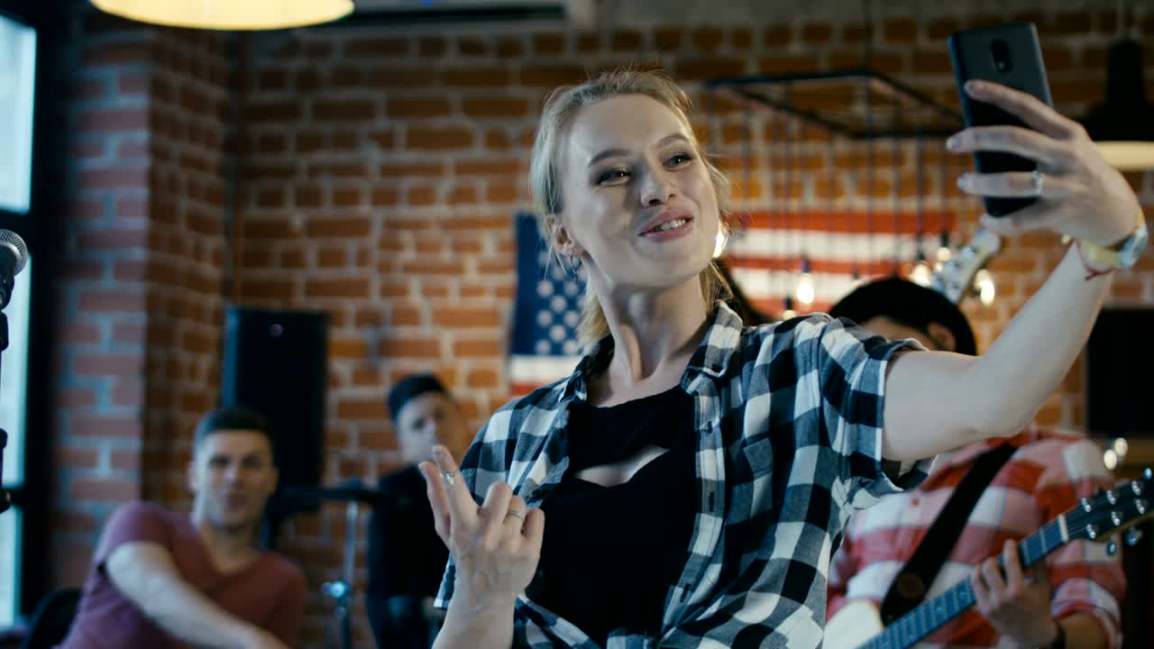 músicos alegres tomando selfies en el escenario