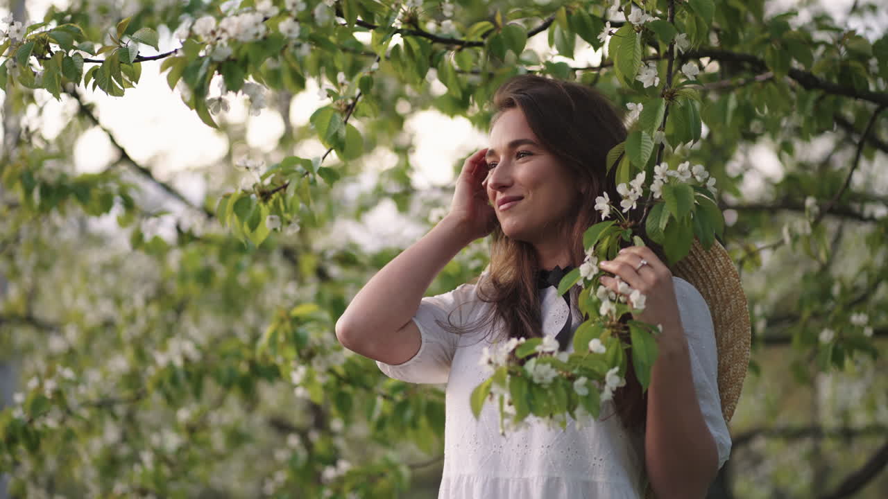 retrato romántico femenino en un jardín en flor en un día de primavera feliz e inspirada mujer en vestido blanco