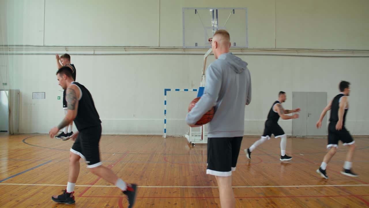 Mænd der spiller basketball i et fitnesscenter