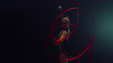 graceful gymnast performing with ribbon indoors. woman practicing gymnastics.