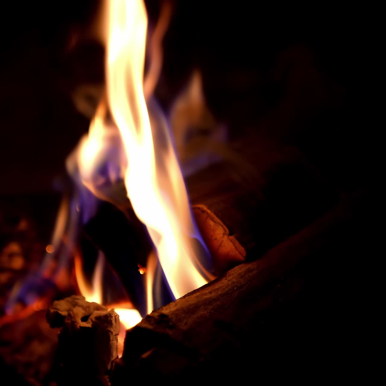 Warm cozy burning fire in fireplace. Burning fire and flames on black background. Flames and burning sparks. Fire patterns. Glow of fire in the dark with copy space. Close-up shot