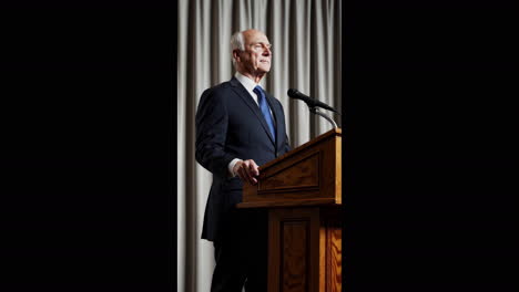 elderly man giving a speech at a podium