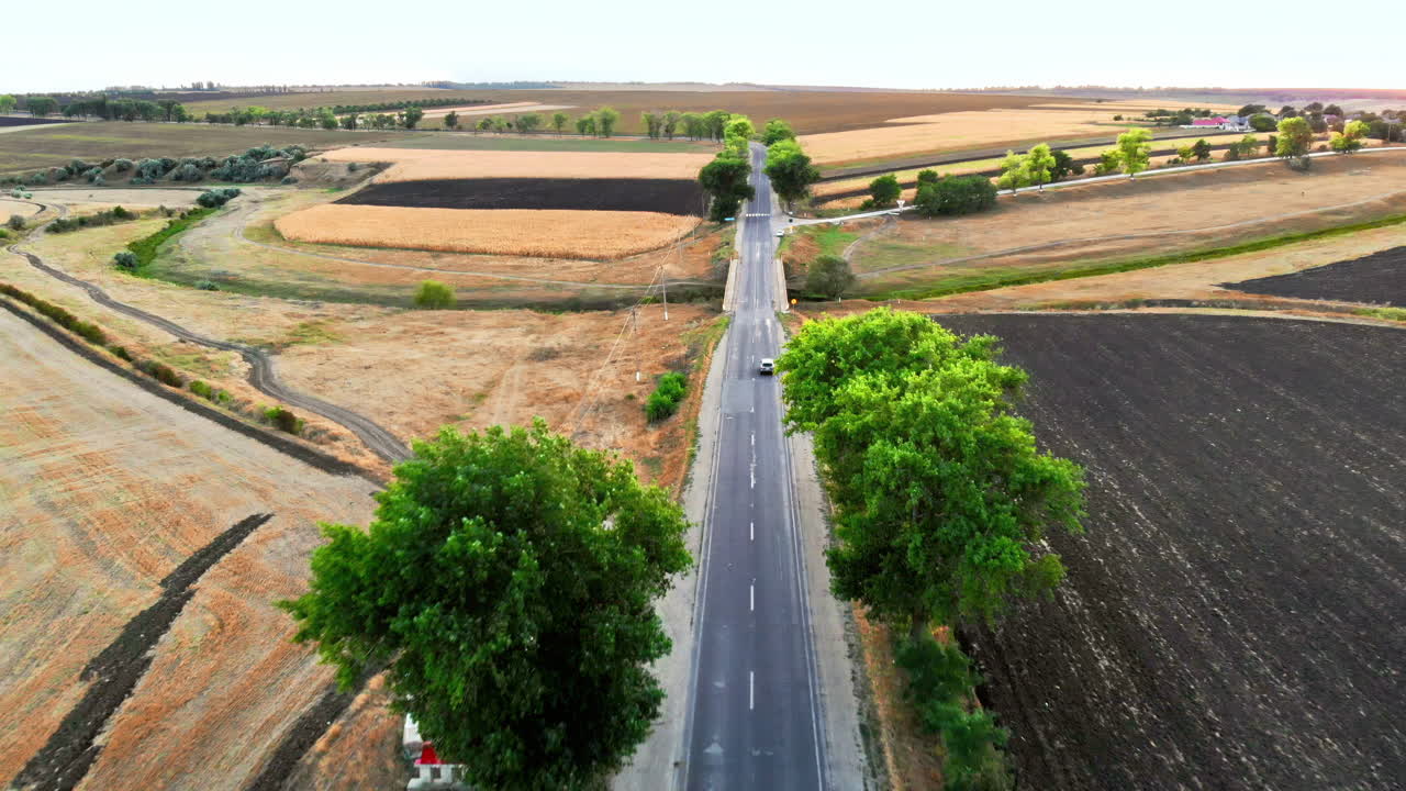 Aerial drone view of a road with moving car in highland. Green fields and hills from north part of Moldova