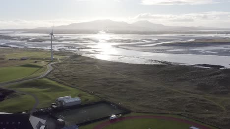 Descending-drone-shot-of-the-coastline-of-Benbecula,-revealing-the-local-track-and-football-pitch