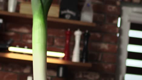 tracking video of tossing leek in the kitchen.