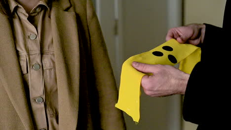 man putting an yellow armband with three black points on a blind woman