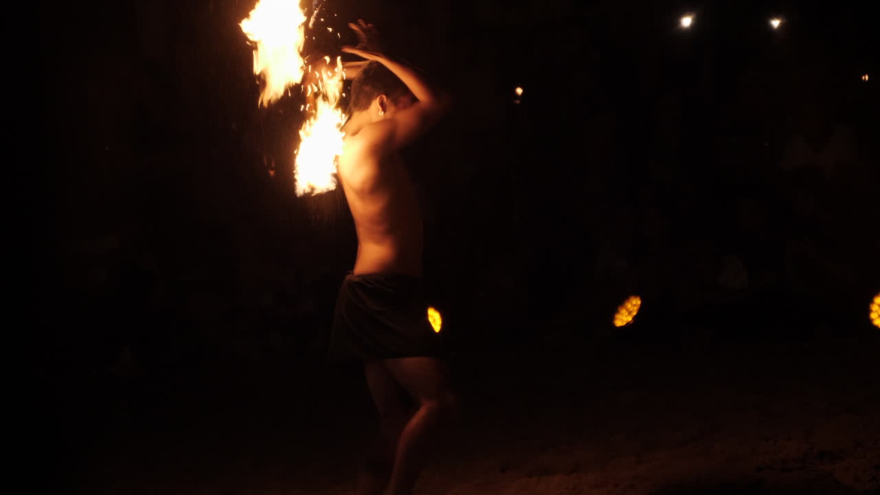 Slow-motion of Polynesian fire dancer showing off twirling flame torches
