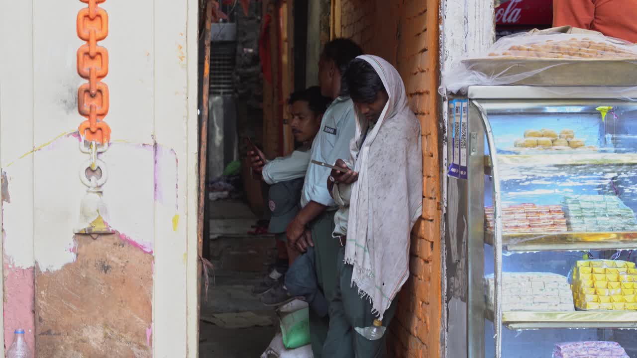 Group of Young Indian men using smart phones in their free time at a street corner, Side Profile