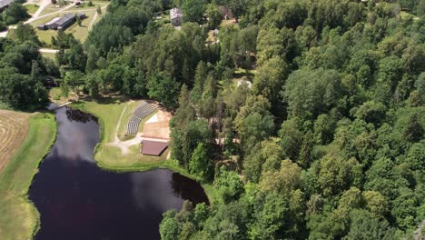 Aerial-view-of-Diklu-Stage-in-Dikli-village,-showcasing-the-open-air-performance-venue-surrounded-by-lush-greenery-and-nearby-buildings