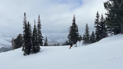 Skiers-skiing-by-on-a-calm-ski-resort-path-surrounded-by-pine-trees-in-the-beautiful-Rocky-Mountains-of-Utah-during-a-sunny-snowstorm-on-a-spring-day